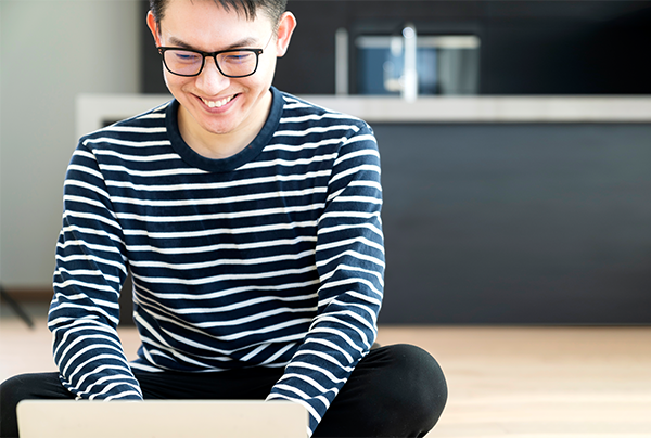 戴著眼鏡、愉悅地操作筆電的男性