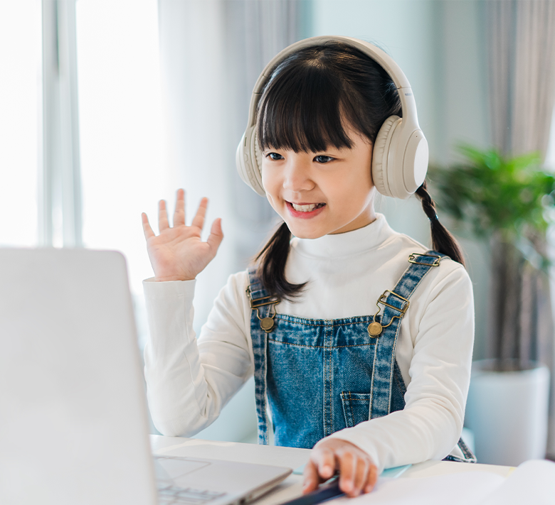 戴著耳機一邊揮手，一邊面向電腦進行英語會話的女孩