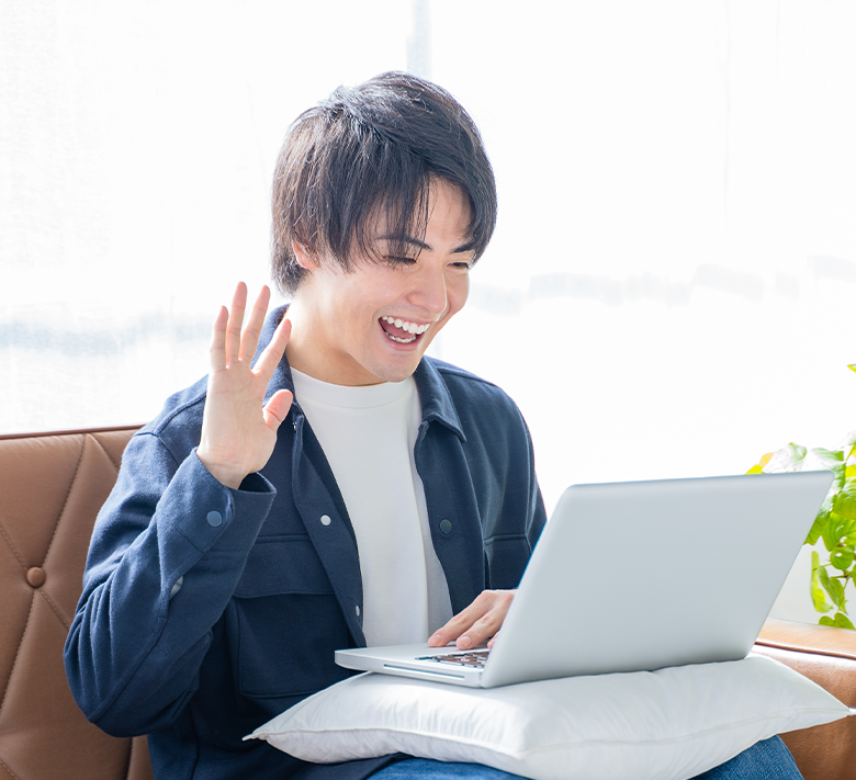 對著筆電揮手、進行英語會話的年輕男性