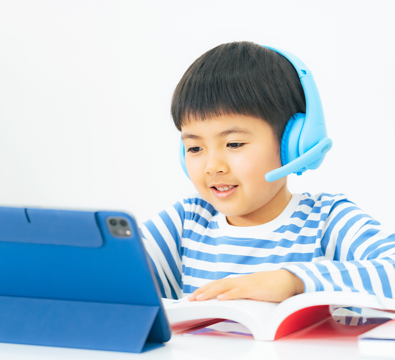 戴著耳機、一邊看著平板一邊學習的男孩