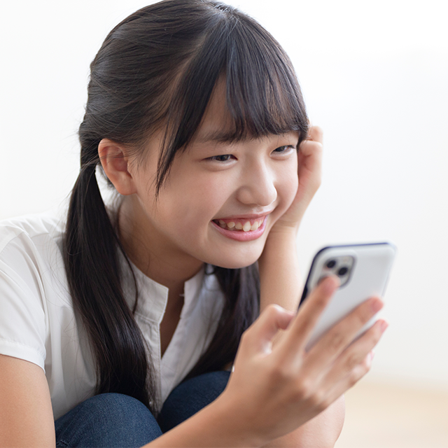 スマートフォンを見ながら笑顔を見せる女子学生