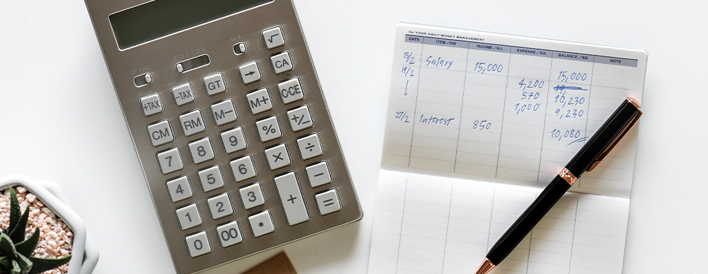 電卓とノートに記入された家計簿、ペン