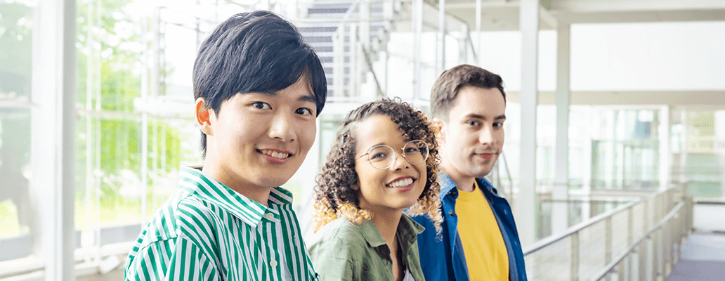屋内で並んで笑顔を見せる3人の若者