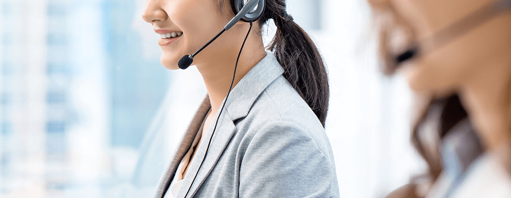 ヘッドセットをつけて笑顔で対応するオペレーター