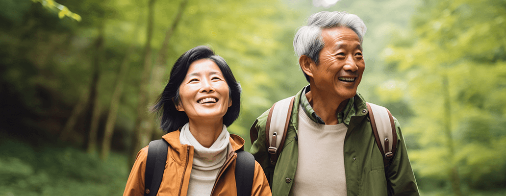 緑の森を背景に笑顔で歩くシニア夫婦
