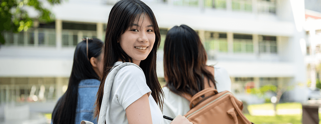 屋外で振り返り笑顔を見せる女子学生