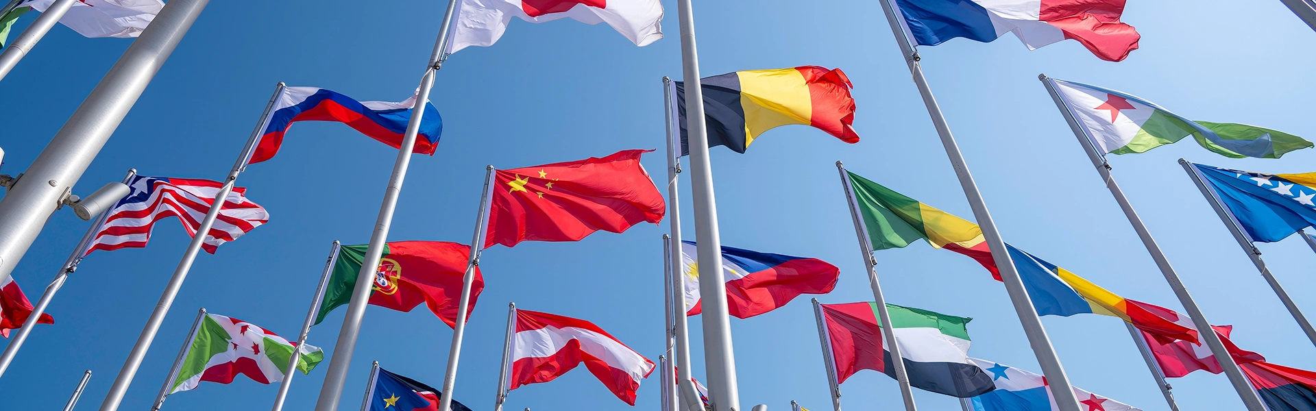 世界各国の国旗が空に掲げられている留学イメージ