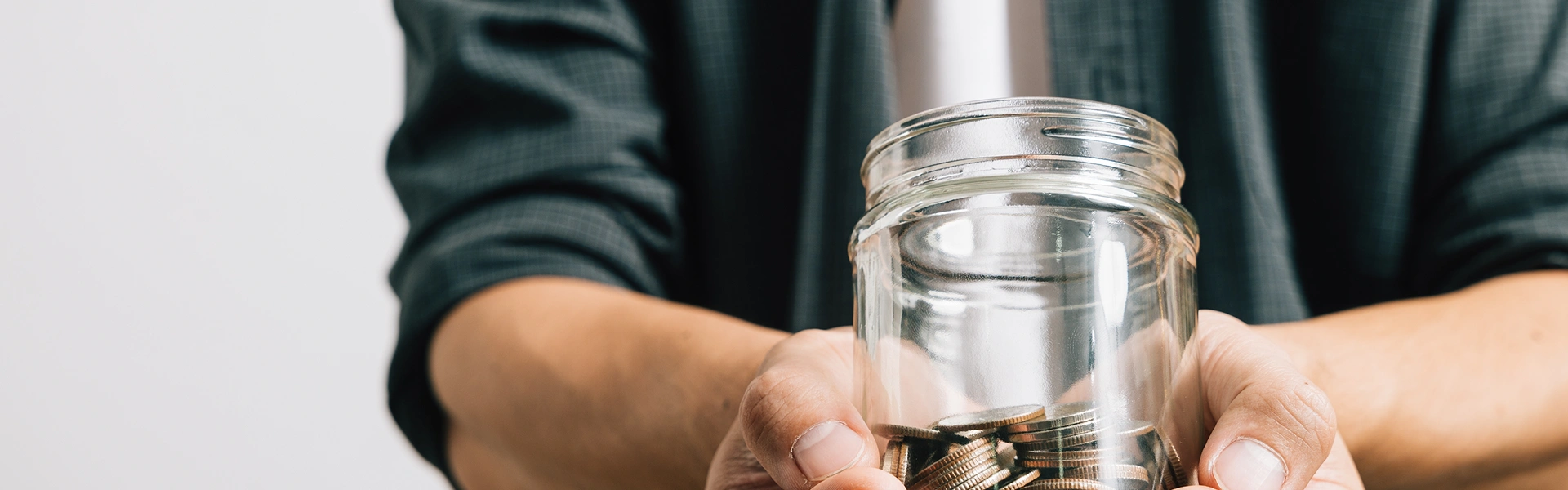 留学費用を考えながら貯金箱を手にする人物のイメージ