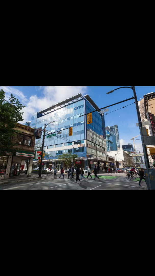 都市部の交差点で人々が横断歩道を渡る、現代的な建物が立ち並ぶ屋外の街並み