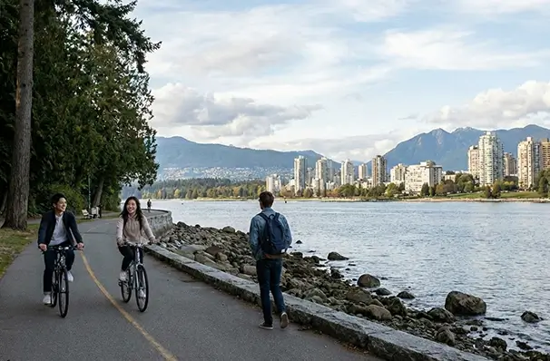 スタンレーパークの海沿いでサイクリングや散歩を楽しむ人々
