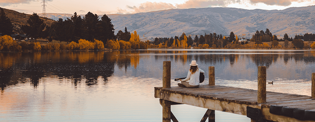 ニュージーランド留学費用のシミュレーション | 自然豊かな湖畔の桟橋に座る学生のイメージ写真