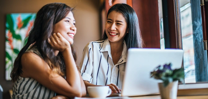 笑顔で会話しながらノートパソコンを見る女性たちの様子