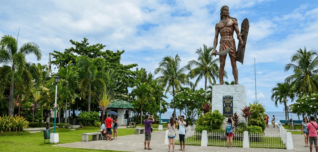 公園内に立つ英雄像と周囲を散策する人々