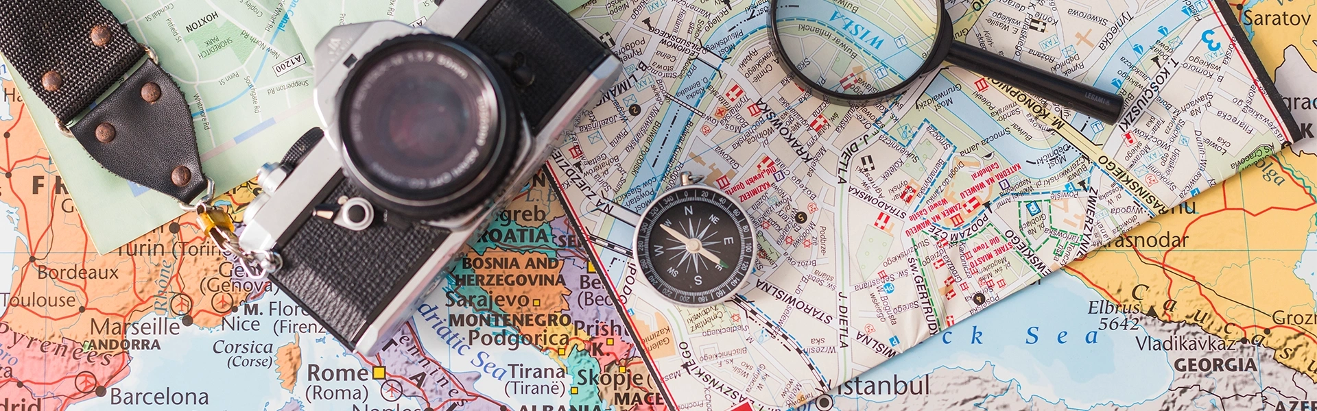世界地図の上に置かれたカメラとコンパス、旅行と海外留学をイメージしたビジュアル