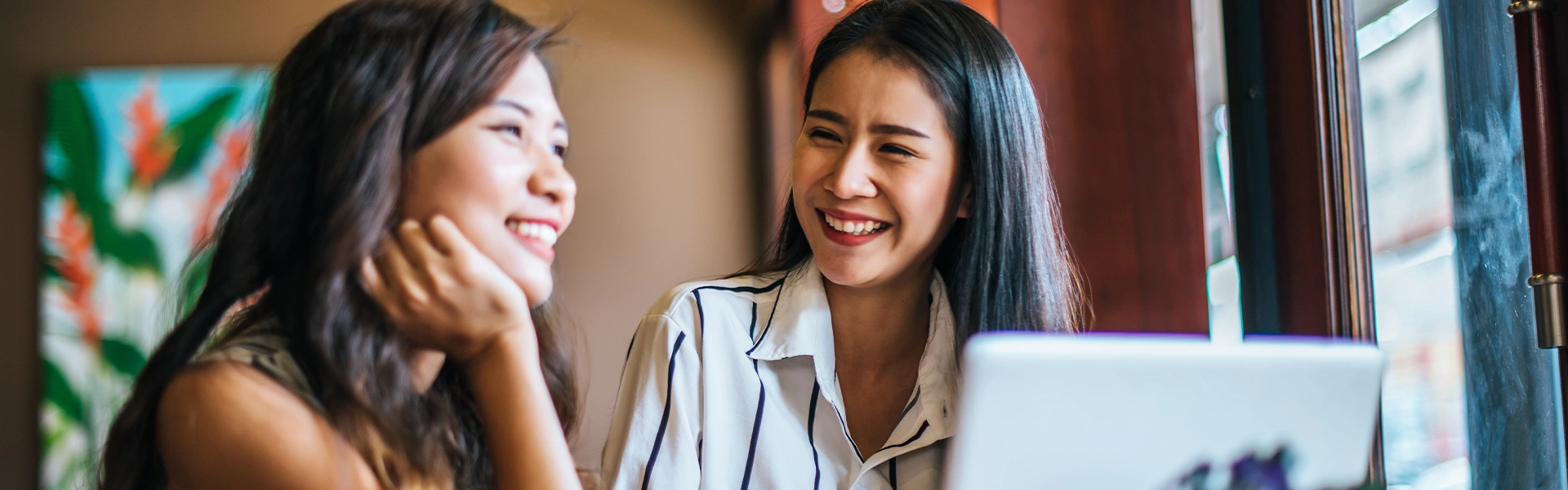 笑顔で会話しながらノートパソコンを見る女性たちの様子