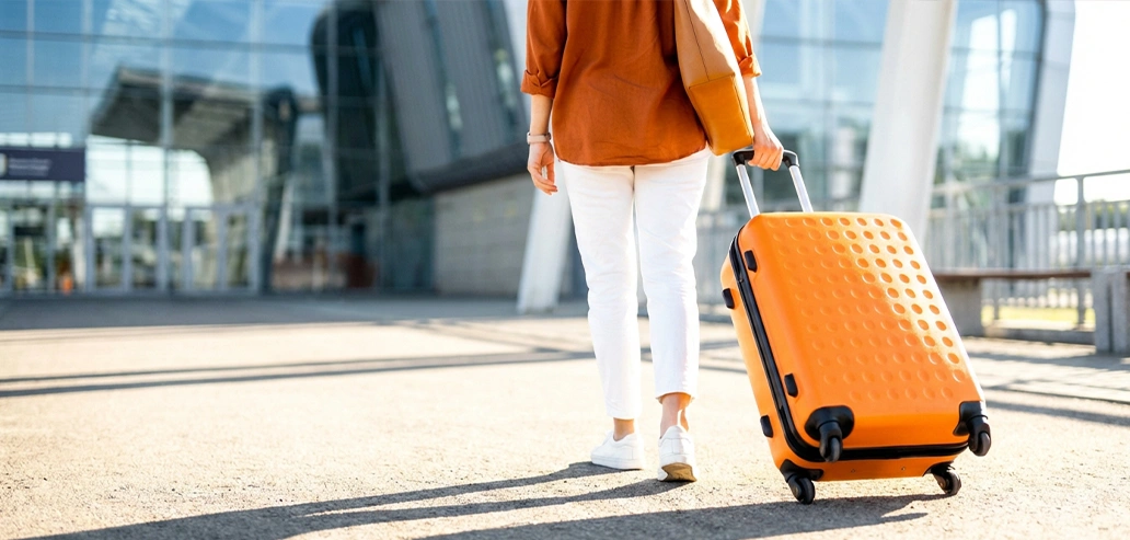 空港でスーツケースを引きながら移動する旅行者の後ろ姿