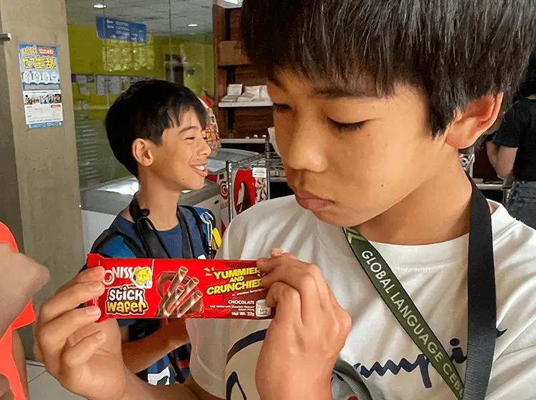 屋内で学生がお菓子を持って笑顔で会話している様子