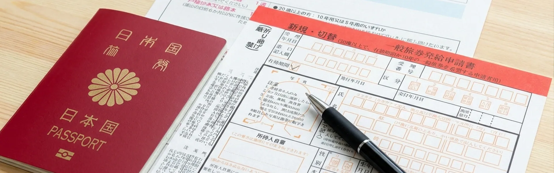日本のパスポートとビザ申請書類、ペンが置かれた書類一式
