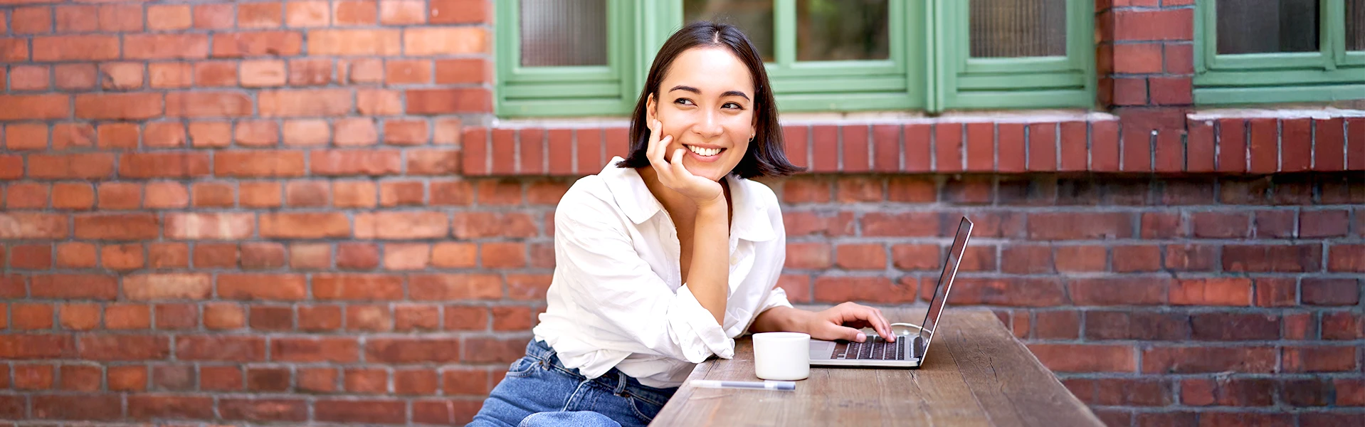 IELTS対策に取り組む女性が屋外でノートPCを使って学習している様子