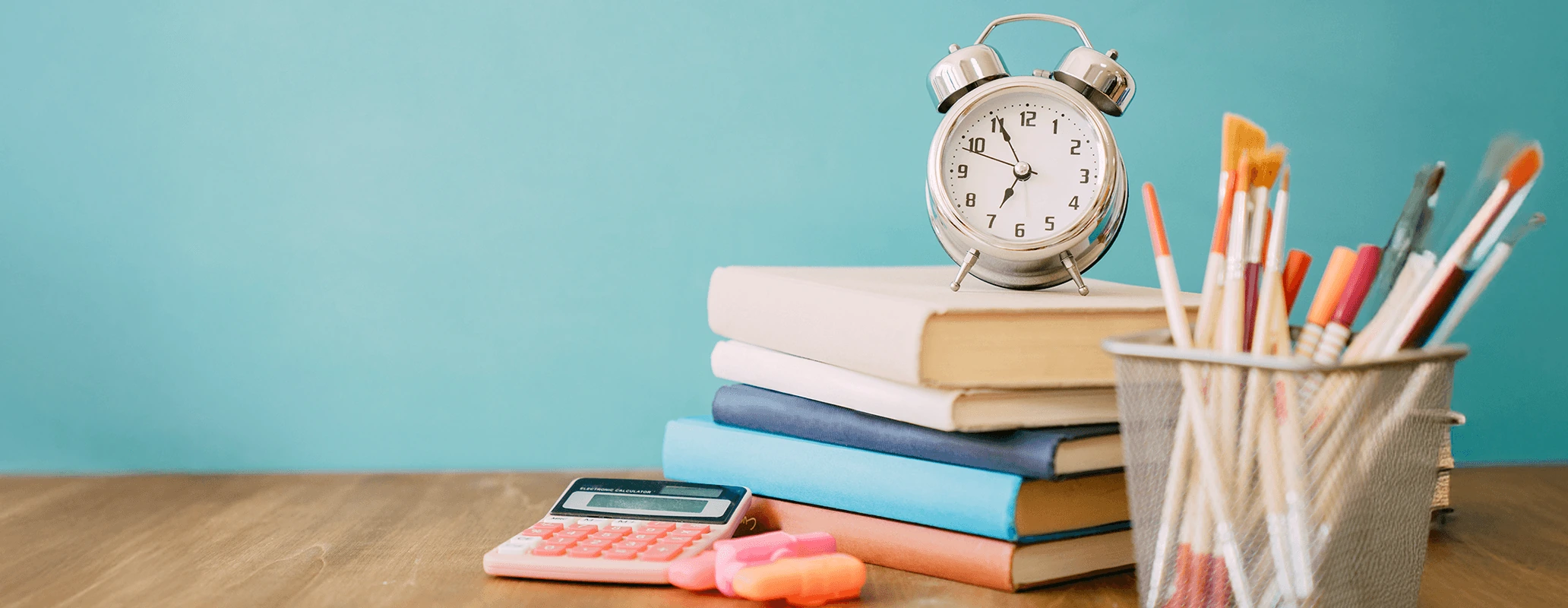 時計と教科書、文房具が並んだ長期留学の準備を示すイメージ