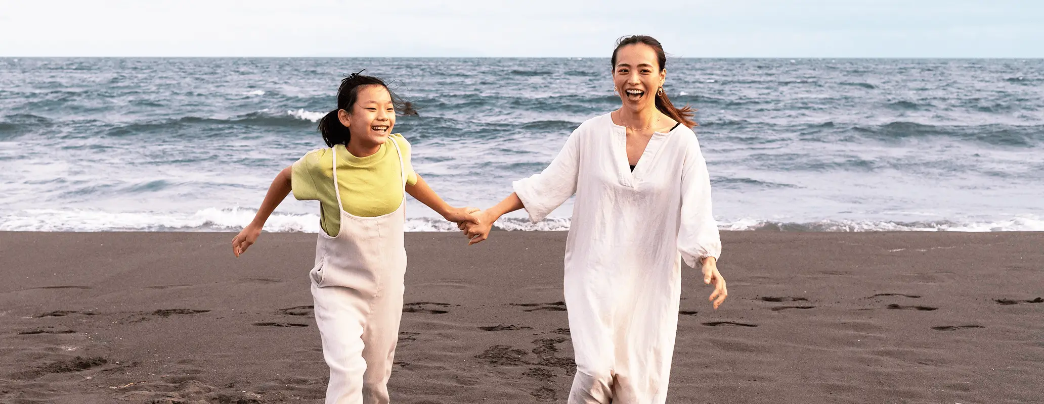 海辺の砂浜を笑顔で走る親子