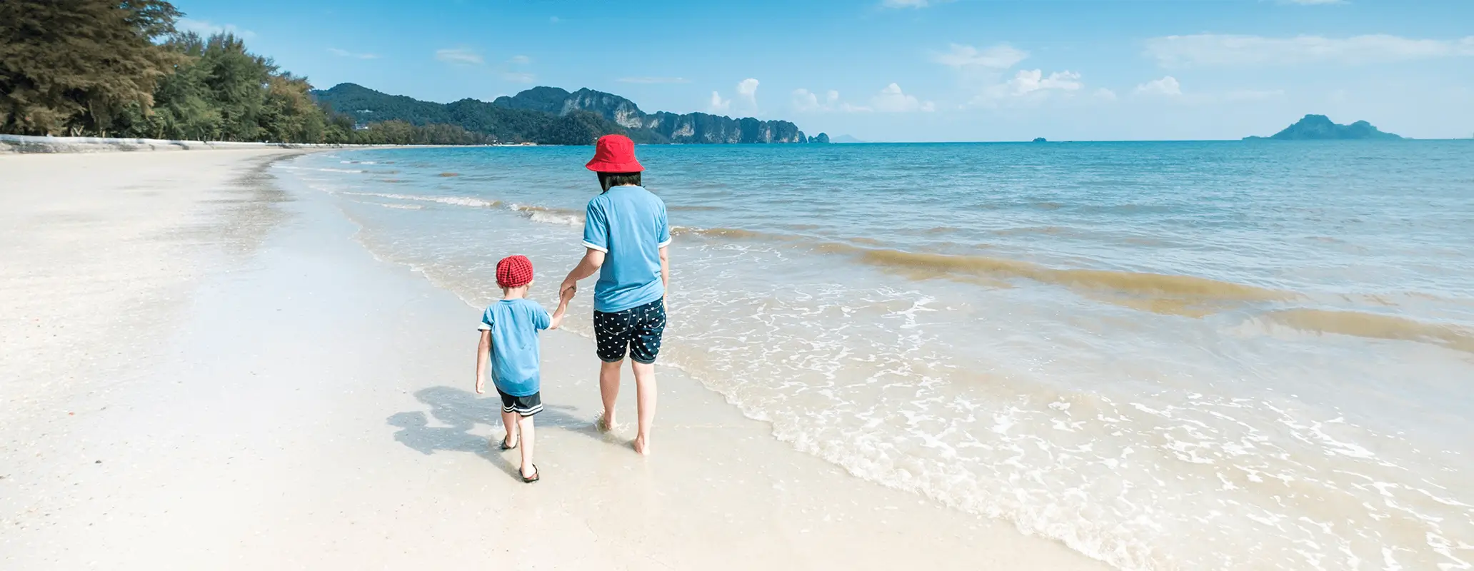 海辺を手をつないで歩く親子