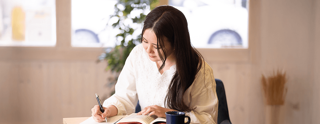 短期留学中にカフェでノートを取りながら学習する女性留学生の様子