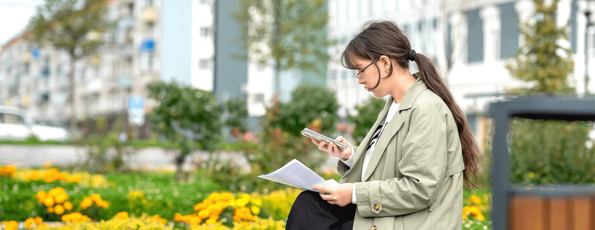 留学情報を確認しながら屋外で学習する女性