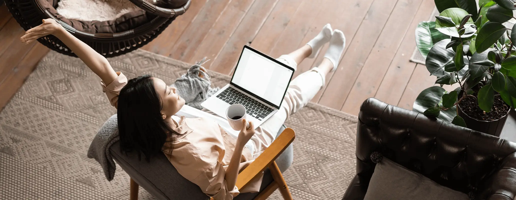 リラックスしながらソファでノートパソコンを操作する女性のワーケーション風景