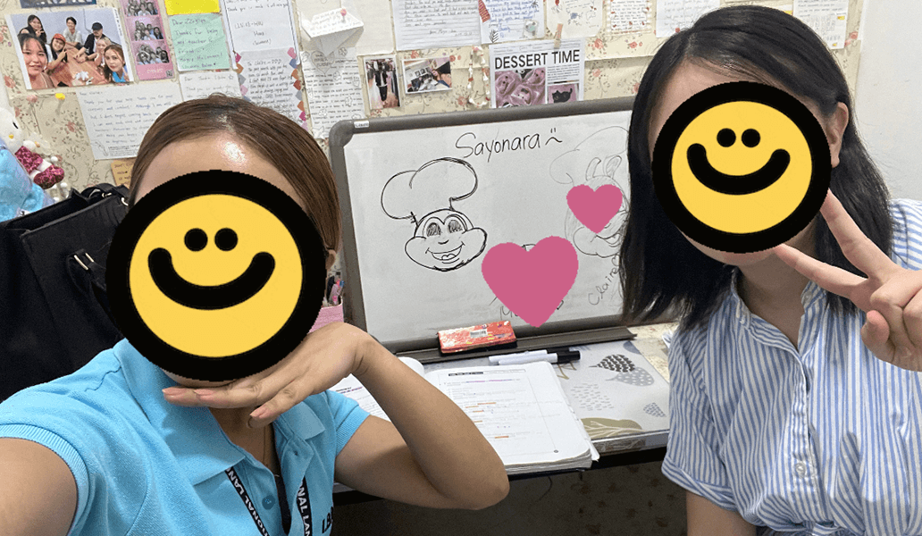 教室で笑顔の学生二人がピースサインをしながらホワイトボードの前でポーズを取っている