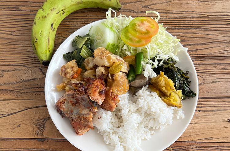 白いご飯と野菜、肉料理が盛られた白い皿とバナナの食事