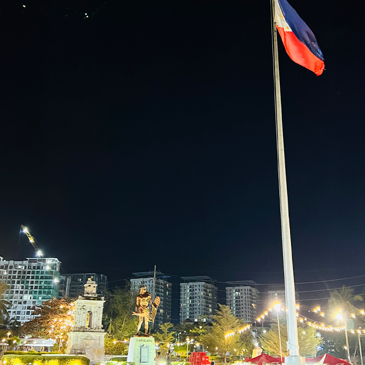 夜空に掲げられた国旗と記念碑、背景に建物群の夜景