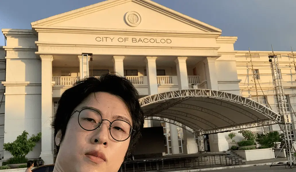 「CITY OF BACOLOD」と刻まれた市庁舎前でセルフィーを撮る女性