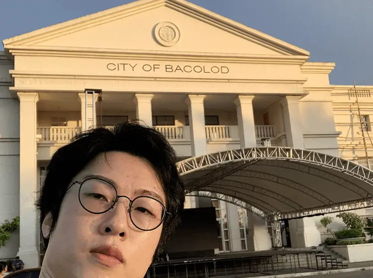 「CITY OF BACOLOD」と刻まれた市庁舎前でセルフィーを撮る女性