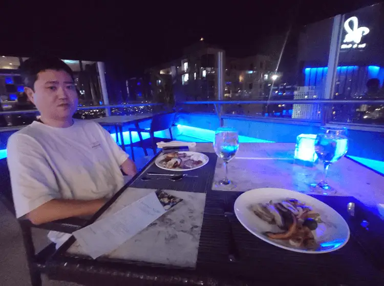 青いライトが灯るルーフトップレストランでの食事風景