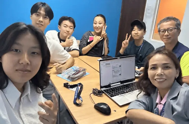 パソコンを囲んでピースサインをするGLCの生徒たち