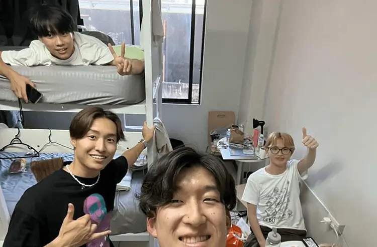 ピースサインで笑顔の2人の男性、室内にて