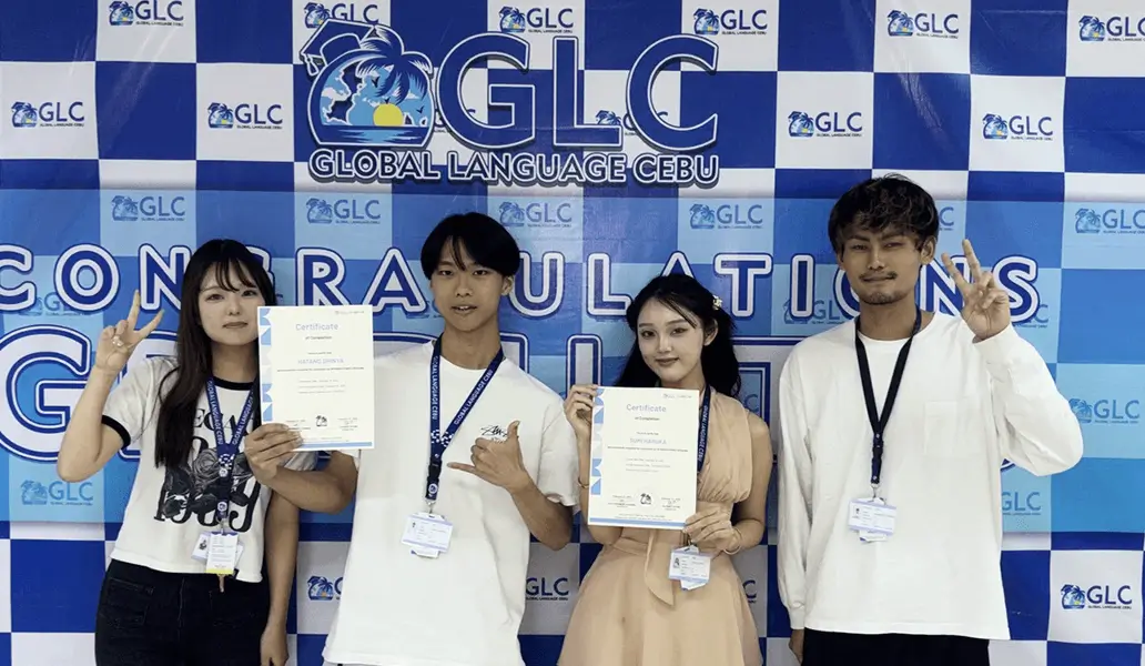 GLC（Global Language Cebu）の垂れ幕前で修了証書を持つ留学生たち
