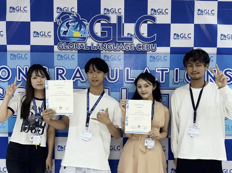GLC（Global Language Cebu）の垂れ幕前で修了証書を持つ留学生たち