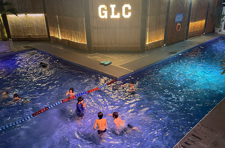 GLCと書かれた建物の屋外プールで人物が泳いでいる