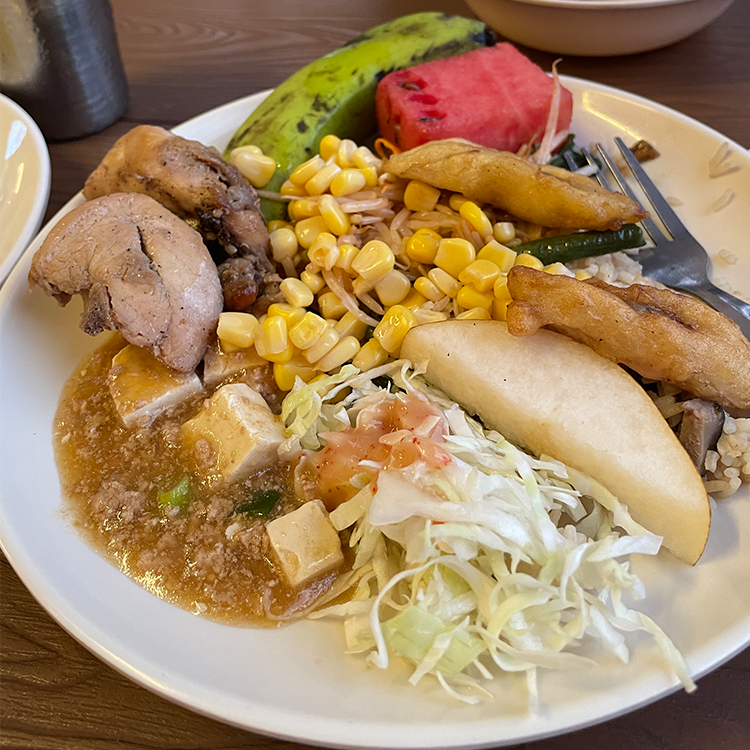 白い皿に盛られた野菜、肉、コーンなどの多彩な食事