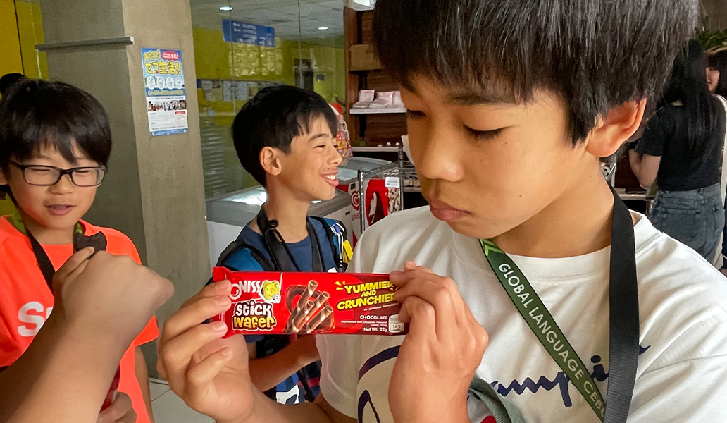 屋内で学生がお菓子を持って笑顔で会話している様子