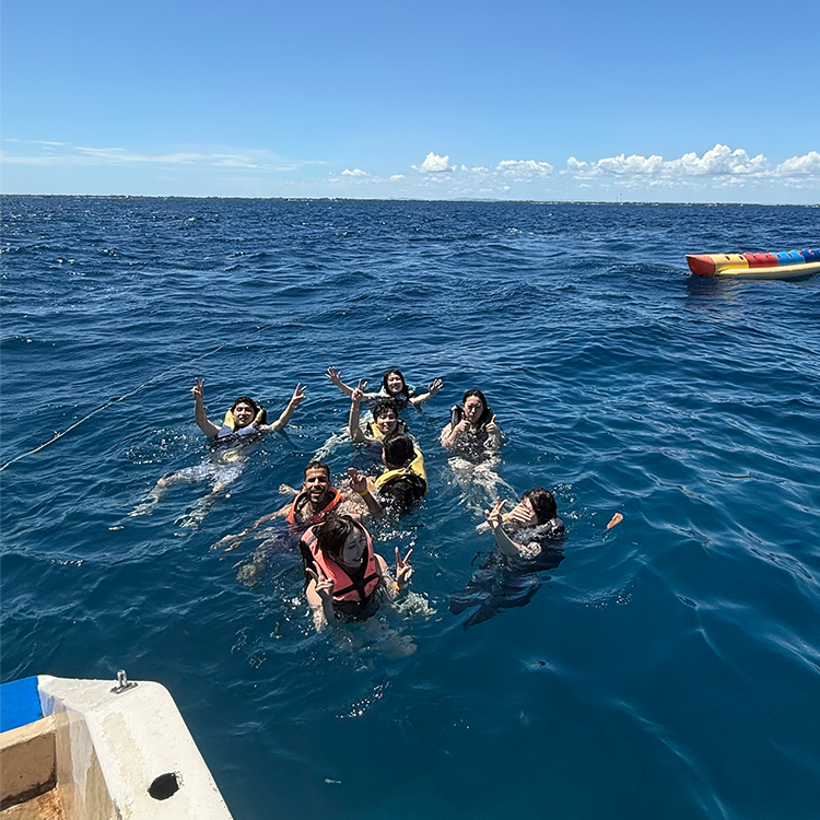 青い海で泳ぐ8人のグループ、手を上げて笑顔の屋外アクティビティ