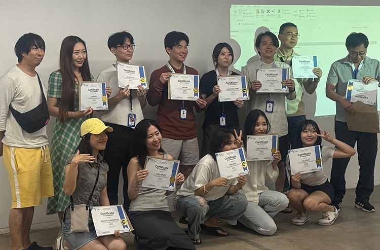 証明書を持つ学生たちの屋内グループ写真、教室での様子