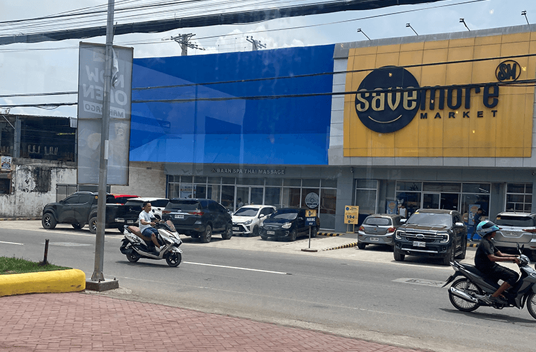 ショッピングモールの建物前で車やバイクが通る屋外の街の景色