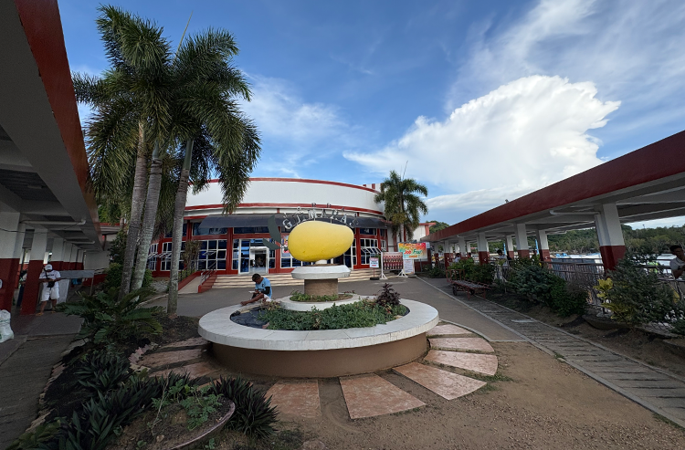 赤と白の建物とマンゴー像がある円形庭園の屋外景色、ヤシの木と青空