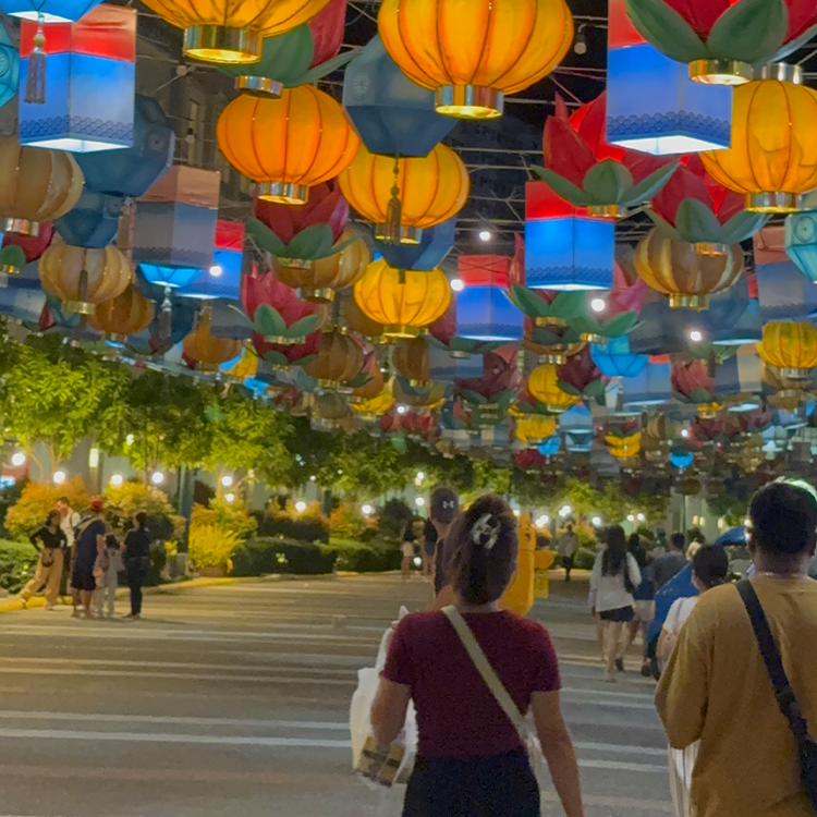 カラフルなランタンが天井に吊るされた屋外の夜景で人々が歩いている
