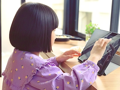 タブレットでオンライン英会話用コンテンツを楽しむ小学生の女の子