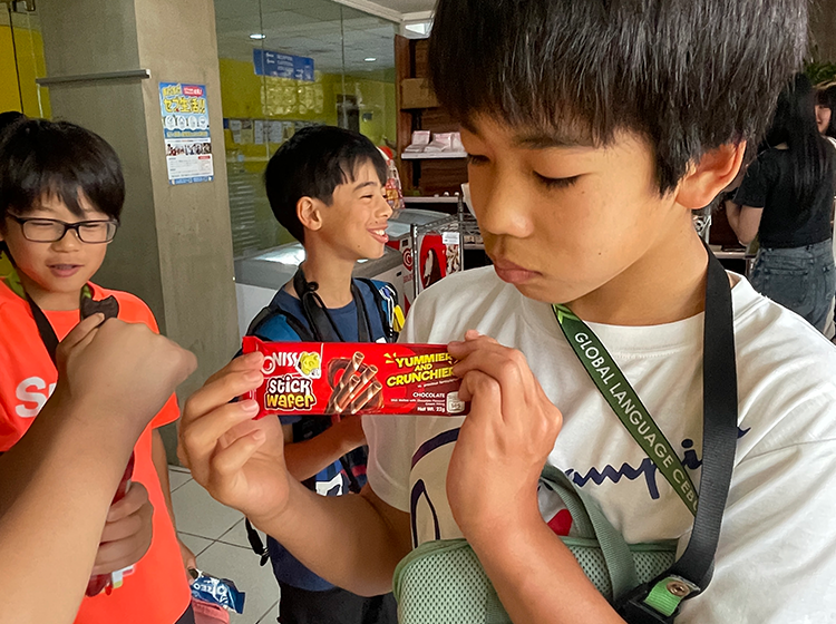 屋内で学生がお菓子を持って笑顔で会話している様子